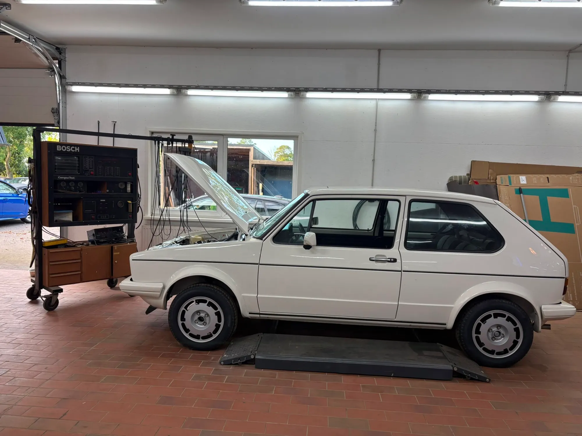 Weißer VW Golf I GTI mit geöffneter Motorhaube in der Seitenansicht