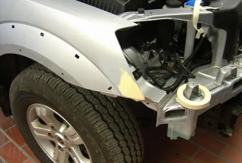 Silbernes Fahrzeug mit geöffnetem Kotflügelbereich während der Reparatur