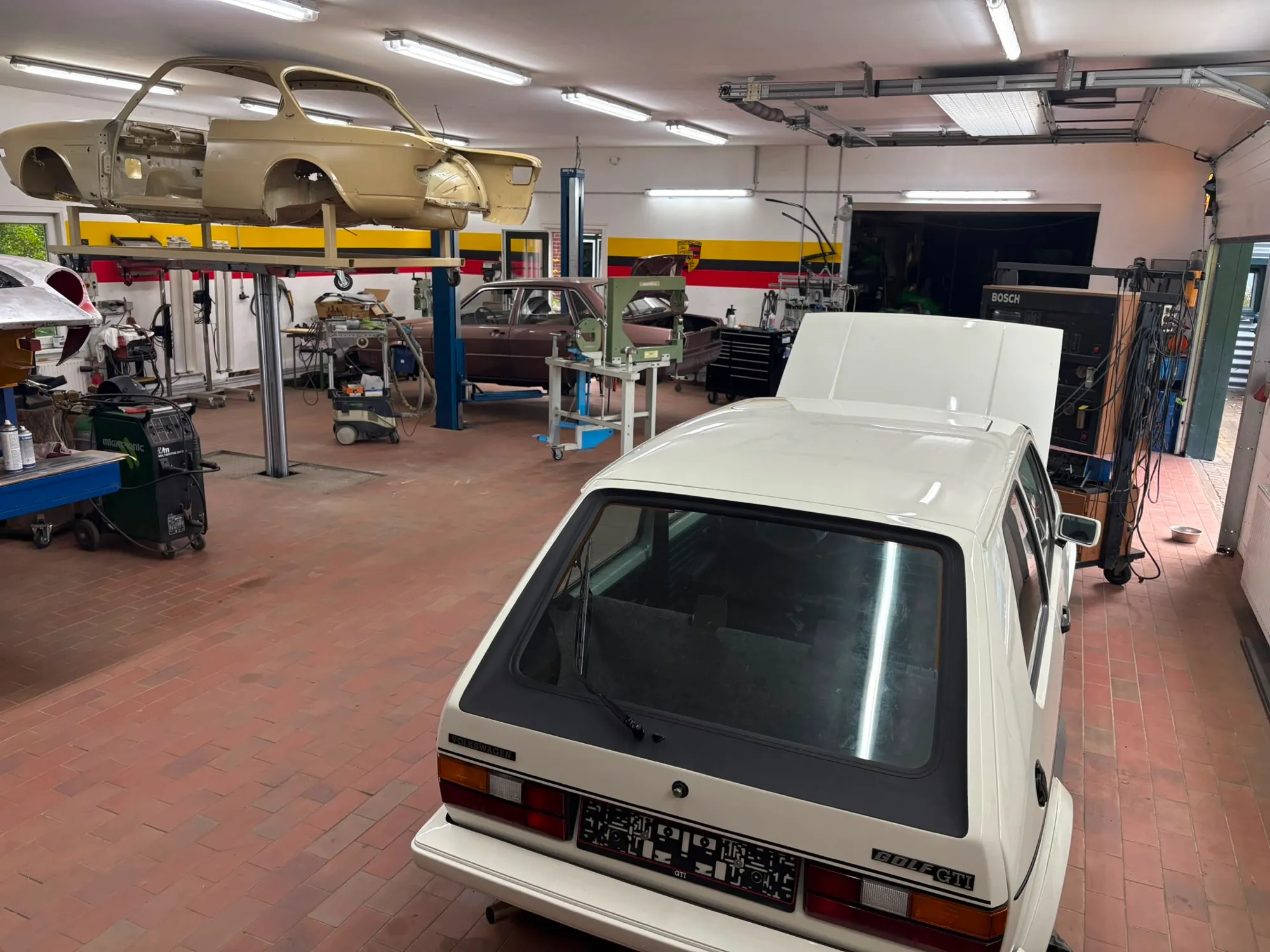 Blick in die Werkstatt mit Oldtimer-Karosserie auf der Hebebühne